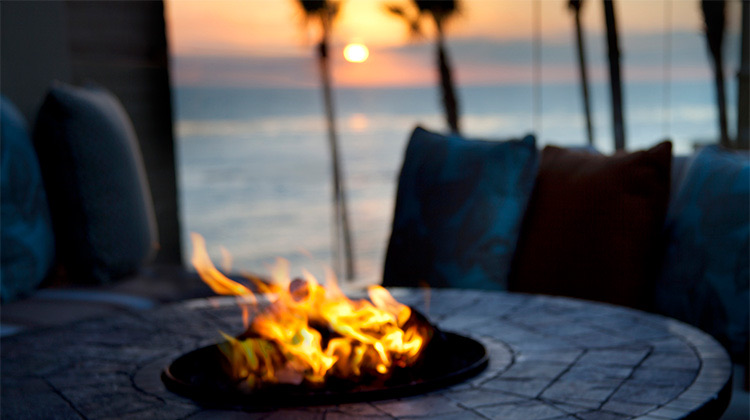 view of a fire-pit surrounded by a blue couch at sunset