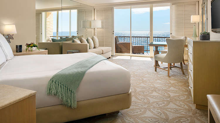 corner view of bedroom with living area and balcony in the background