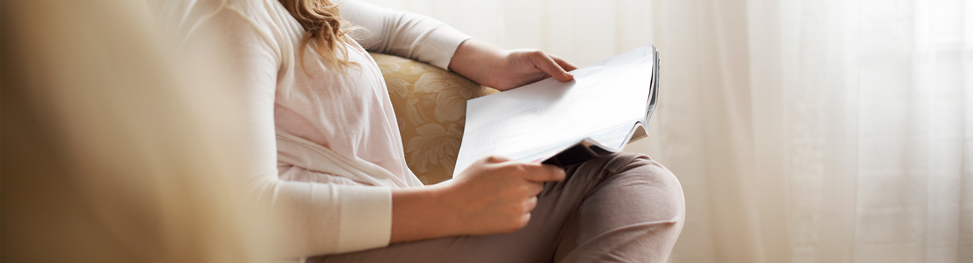 woman sitting on the couch reading a magazine