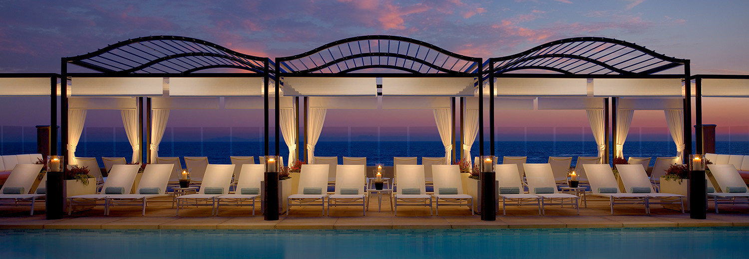 sunset image of pool with seating and cabanas