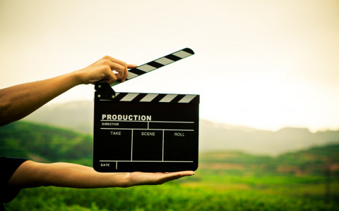 clapperboard between hands in outdoor landscape