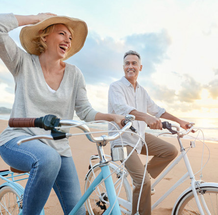 older couple bike riding on the beach