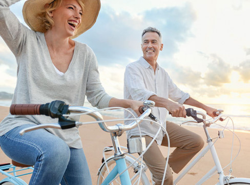 older couple bike riding on the beach