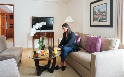 lady working on her laptop on the sofa within her hotel suite
