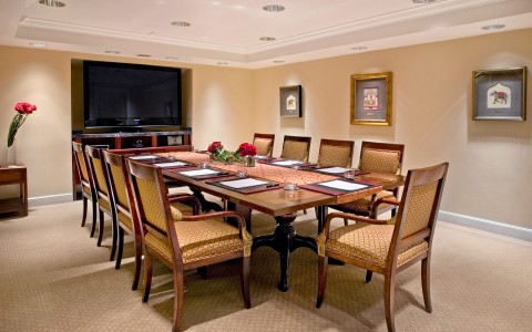 large conference room with tv screen included and dark brown tones around the room