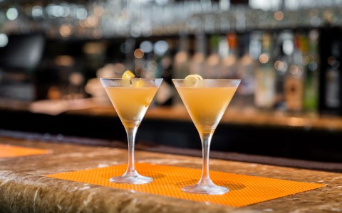 two orange-colored cocktails on top of the bar