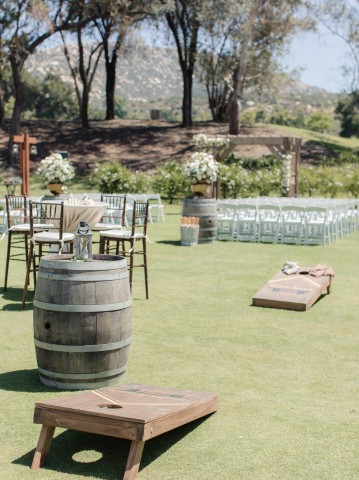 cornhole with greenery ceremony setting in the back