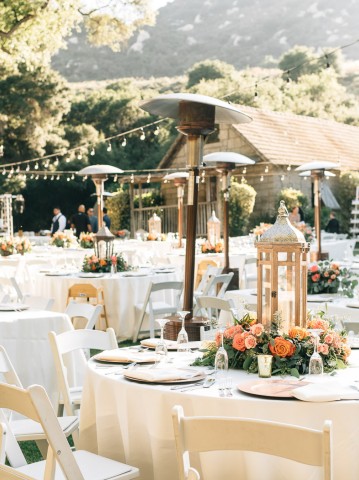 outdoor wedding tables with white tablecloths, string lights, and heaters