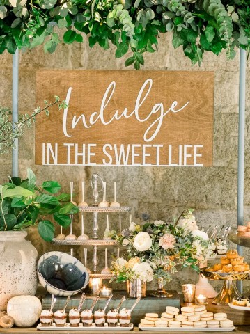 wooden sign above a dessert table at a wedding
