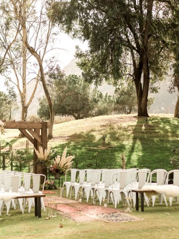 outdoor wedding set up with white chairs and wooden accents