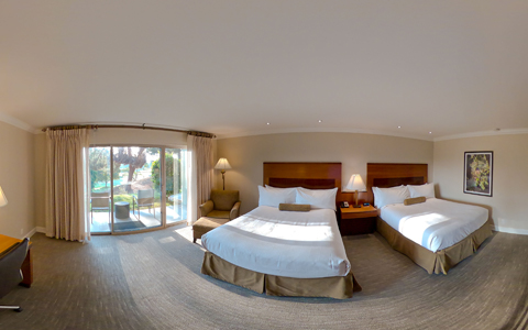 wide-shot view of two large beds in spacious room with balcony