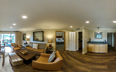 wide view of room common area featuring a couch, two armchairs, kitchenette and connecting balcony
