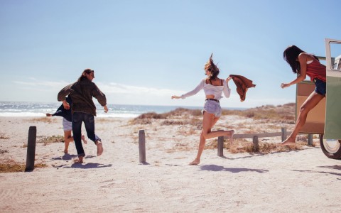 people jumping and running onto the beach in the daytime