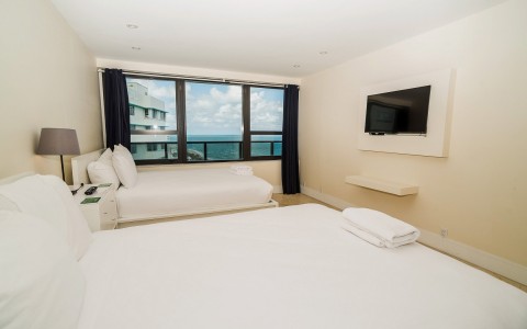 2 Queen & 2 Twin room with a tv and a view of the ocean
