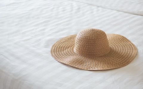 sun hat sitting on a white bed