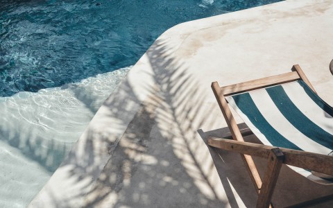 close up of the pool desk with palm tree shadow and the pool chair in view 