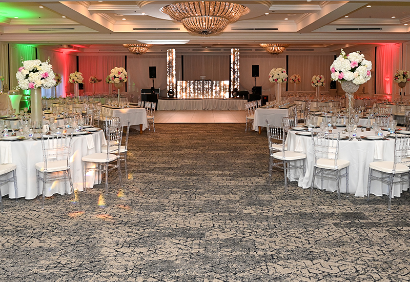 indoor event space with carpet and round tables set up on both sides of the room