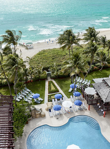 
                            aerial image of the back of the property with a view of the ocean, pool, outdoor restaurant and lounge chairs 