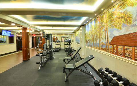 Inside hotel gym with workout equipment with beach painting on the wall 