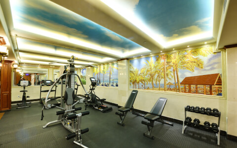 Inside hotel gym with workout equipment with beach painting on the wall 