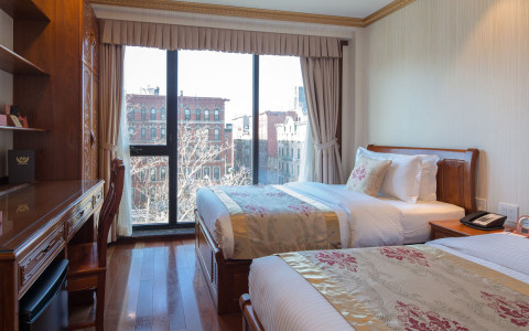 Interior hotel room with double beds and ceiling to floor windows looking over the city