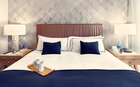 A king bed with white and blue pillows with a nightstand on each side.