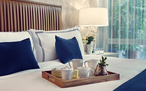 close up of  king bed with a food tray on it holding coffee mugs and cookies