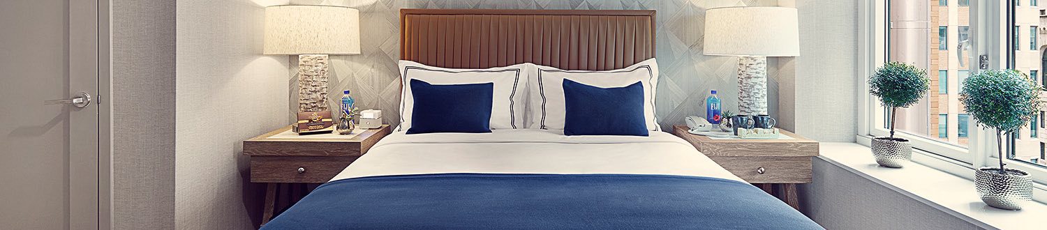 A queen bed with white and blue pillows with a nightstand on each side