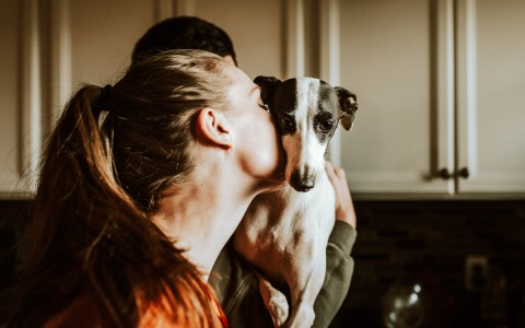 woman kissing a small dog