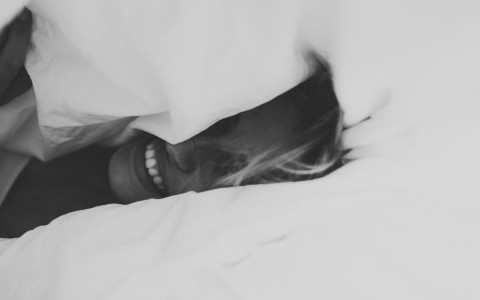 greyscale picture of woman laying on bed