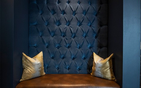 dark blue walls with gold accents and a brown leather bench
