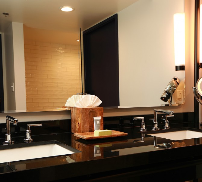 black countertop in bathroom with two sinks and a box of tissues in the center