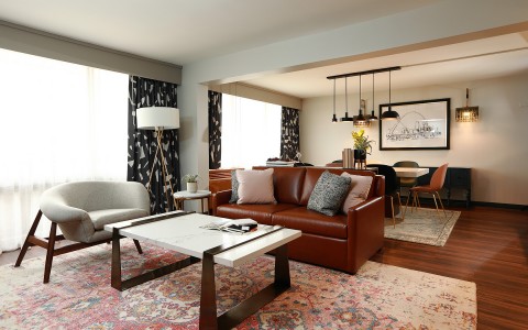 suite living room with brown sofa and modern coffee table with marble detail