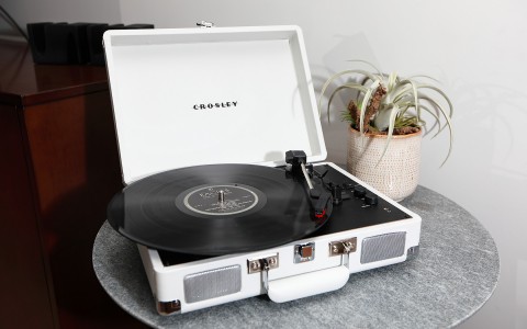 white crosley record player on a round grey marble table with a plant next to it