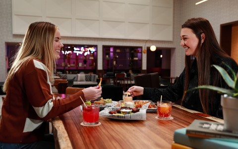 two girls enjoying food and cocktails in hotel restaurant