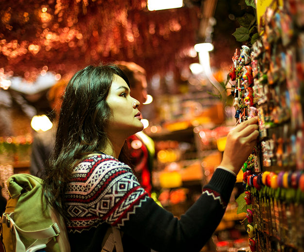 a girl in a store looking at magnets for a souvenir 
