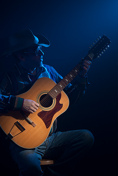 man playing the guitar with blue lighting