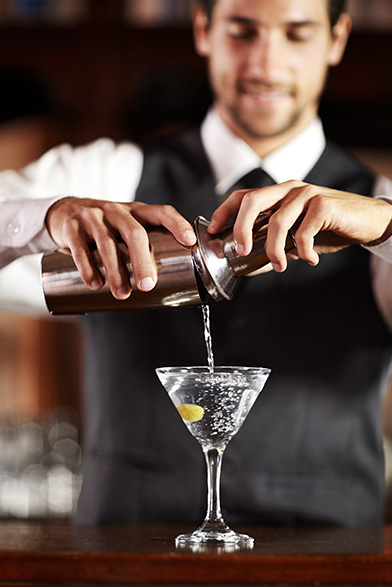 man pouring a martini from a shaker into a glass