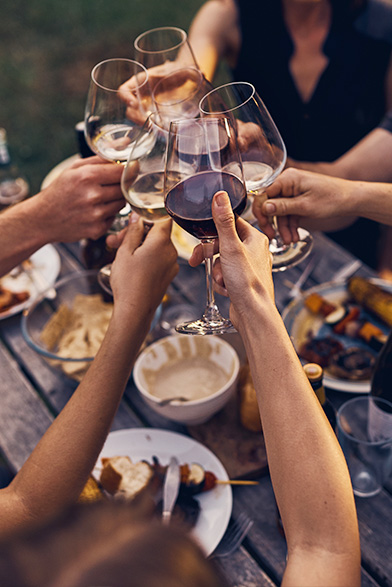 couples cheering wine glasses over a wooden table
