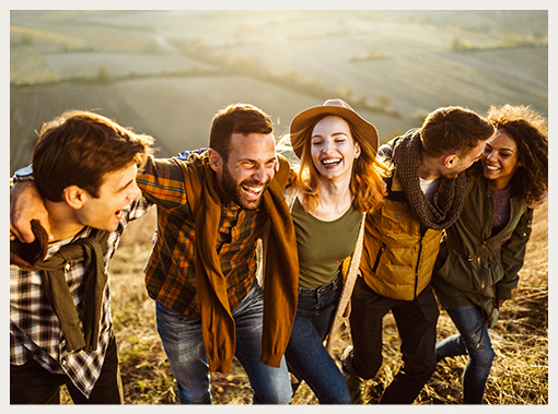 five people laughing and walking up a hill together