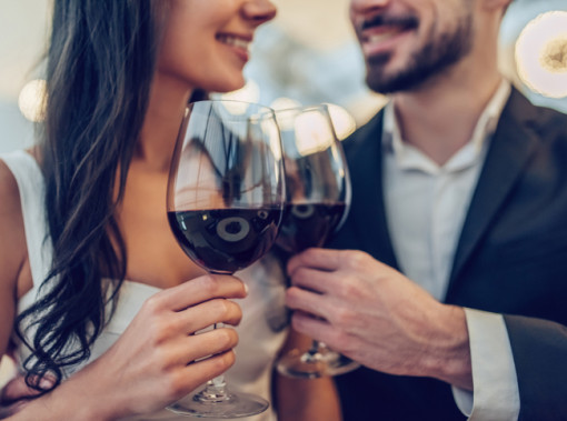 man and woman holding wine glasses wearing fancy clothing