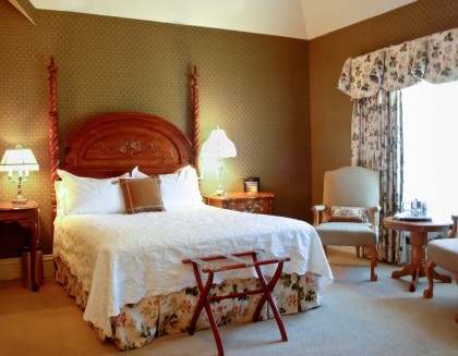 view of bedroom with white bed and floral accents, two nightstands with lamps, two lounge chairs with table 