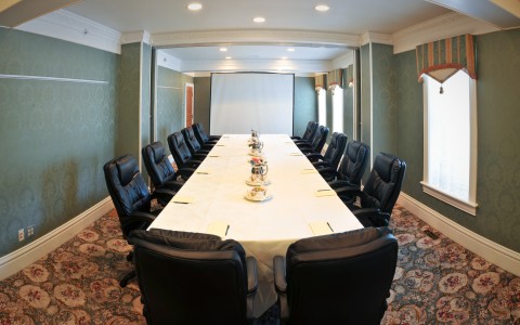 boardroom with long table set up with black chairs 