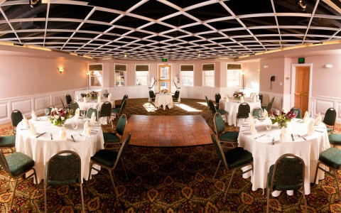 event room set up with a dance floor, tables with chairs around them for a wedding 