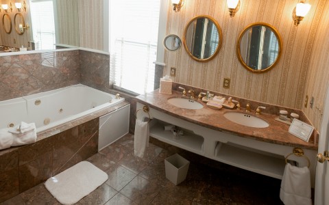 bathroom with tub, two sinks and two mirrors 