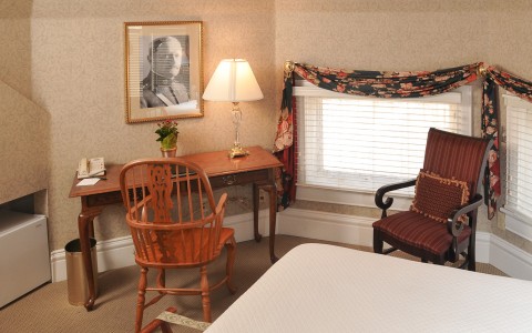 view of desk and chair, lounge chair and windows in bedroom