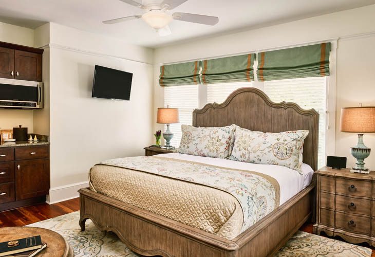 king bed with nightstand, lamp and kitchenette