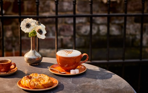 latte and pastry on a table with vase 
