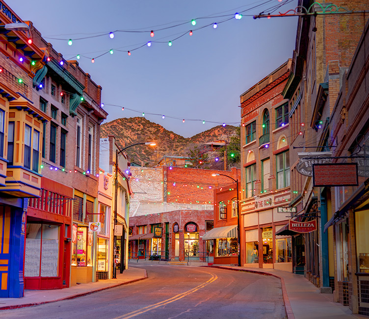 outside of bisbee on a street with christmas lights hanging from the buildings