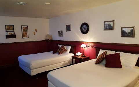 double queen room with maroon carpets and pillows 